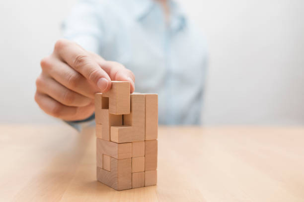 ręka człowieka dodaje ostatni brakujący drewniany blok na miejsce. koncepcja sukcesu biznesowego. - wood toy block tower zdjęcia i obrazy z banku zdjęć