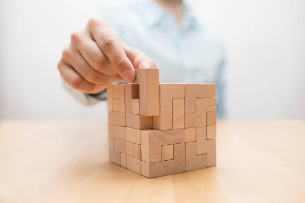 Man's hand adding the last missing wooden block into place. Business success concept. stock photo