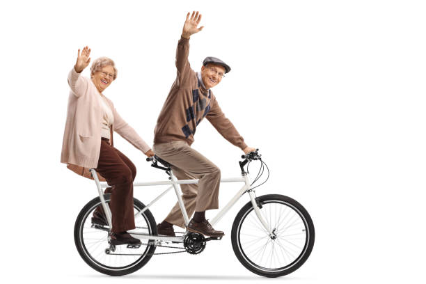 istock Senior couple riding a tandem bycicle and waving 1147515066