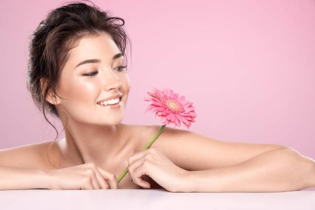 istock Woman at  pink studio background with flowers 1147516289