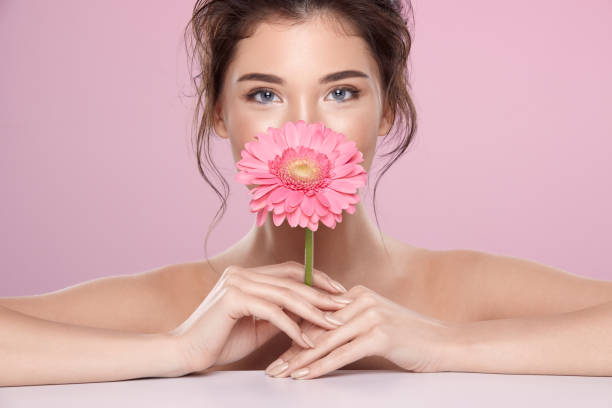 Woman at  pink studio background with flowers stock photo