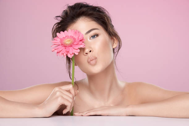 istock Woman at  pink studio background with flowers 1147516314