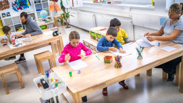 istock Female teacher supervising three students writing into their notebooks 1147517022