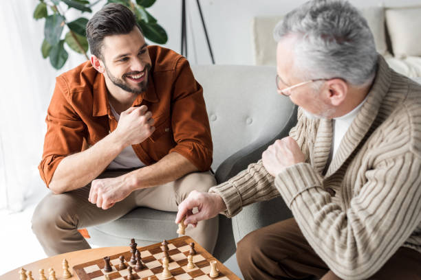 istock retired father in glasses looking at happy son while playing chess 1147518315