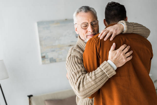 istock senior man in glasses smiling while hugging son 1147518316