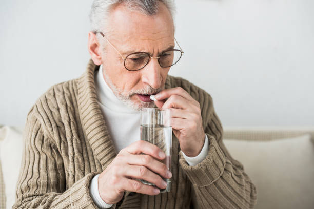 istock senior man in eye glasses taking pill at home 1147518390