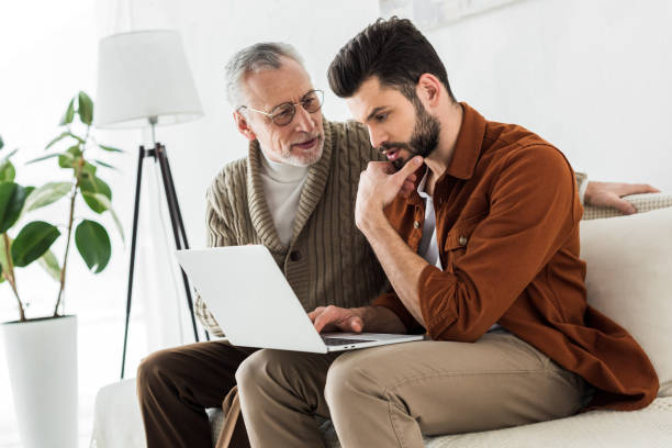 istock senior father looking at handsome son sitting with laptop 1147518420