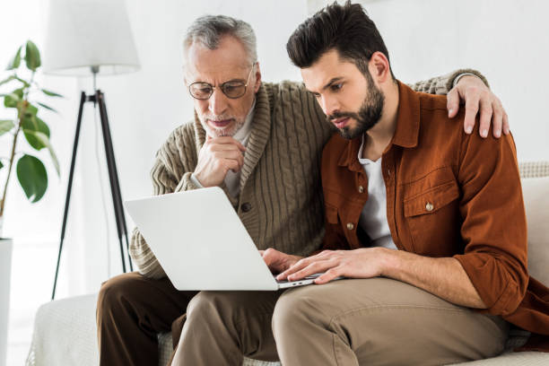 istock handsome man sitting with senior father and looking at laptop 1147518422