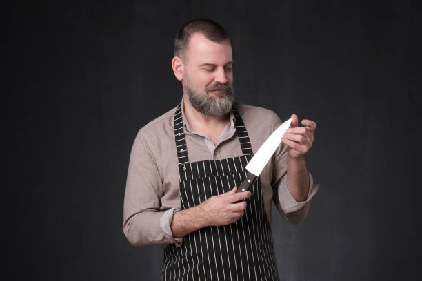 istock Mature chef in apron cook holding knife checking quality 1147520816