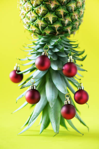 istock Creative Christmas tree made of pineapple and red bauble on yellow background, copy space. Greeting card, decoration for new year party. Holiday concept. 1147521035