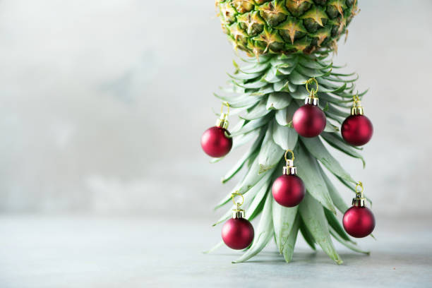istock Creative Christmas tree made of pineapple and red bauble on grey concrete background, copy space. Greeting card, decoration for new year party. Holiday concept. 1147521048