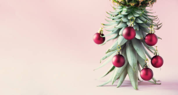 istock Creative Christmas tree made of pineapple and red bauble on pink background, copy space. Greeting card, decoration for new year party. Holiday concept. Banner 1147521055