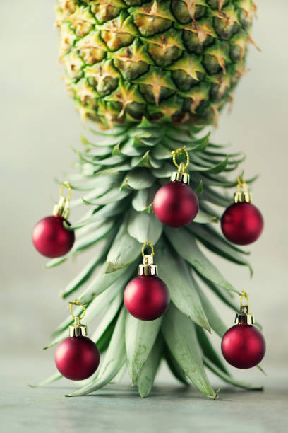 istock Creative Christmas tree made of pineapple and red bauble on grey concrete background, copy space. Greeting card, decoration for new year party. Holiday concept. 1147521057