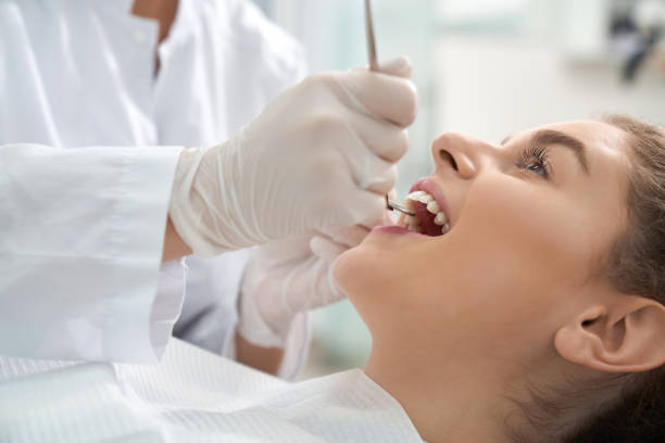 Closeup of woman lying on dental chair with open mouth stock photo