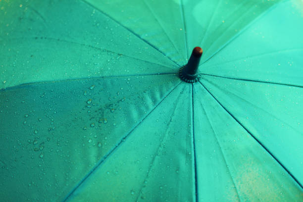 Blue umbrella with rain drops. Autumn weather concept.