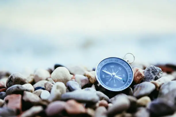 Compass on the beach, small stones, text space
