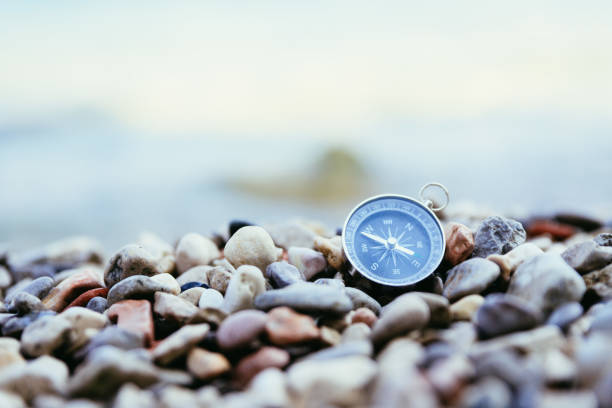Navigation concept: Compass is lying on the beach near the sea