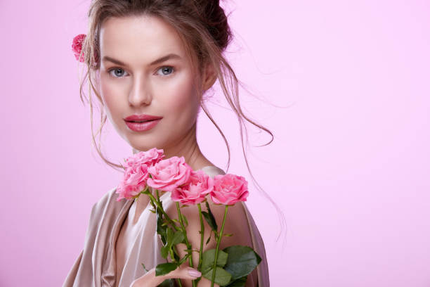 istock Woman with roses at pink background 1147523693