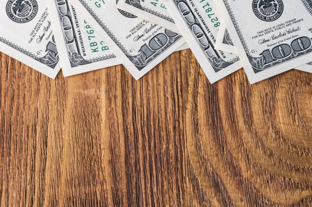 istock Dollar banknotes are lying at wooden background. 1147524510