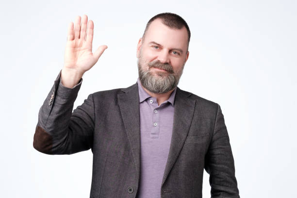 istock Mature man in jacket wave hand welcome. 1147524520