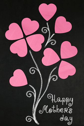 Flowers of paper hearts  and text happy  Mother's day on blackboard