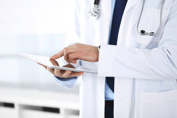 istock Doctor man using tablet computer for network research or virtual disease treatment, hands close-up. Perfect medical service in clinic. Modern  medicine, medic data and healthcare concepts 1147534322
