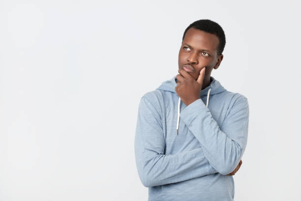 Handsome young African American man looking up with thoughtful and skeptical expression