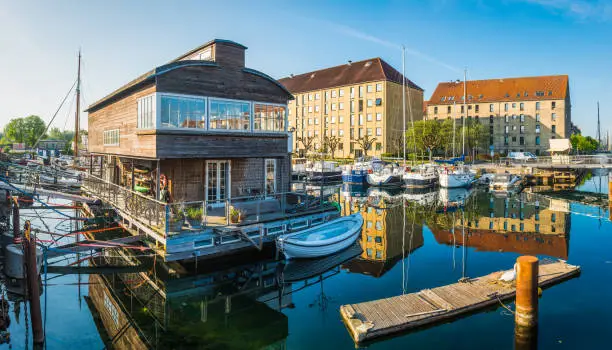 Apartments and yachts reflecting in the tranquil waters of a quiet marina in Christianshavn harbour in the heart of Copenhagen, Denmark’s vibrant capital city.