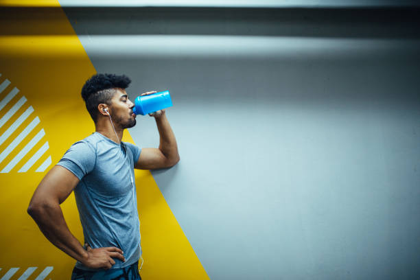 Drinking a water Young african american man drinking a water. protein drink stock pictures, royalty-free photos & images