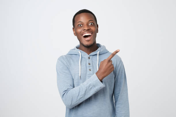 istock Young african guy smiling and pointing finger aside 1147537539
