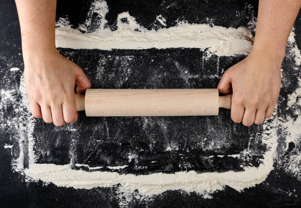 istock wooden rolling pin in female hands on a black background with white wheat flour 1147537708