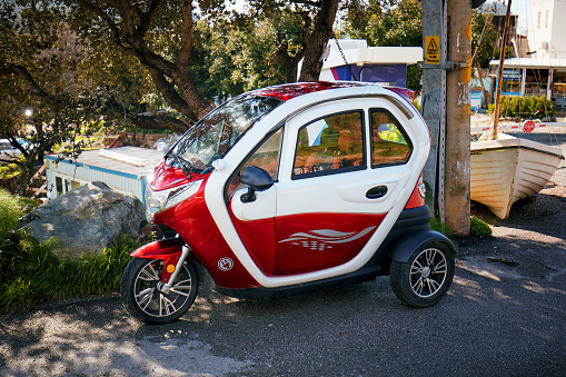 Bodrum, Turkey - January, 2019: Cute small tricycle electric car parked near the asphalt road. Editorial.