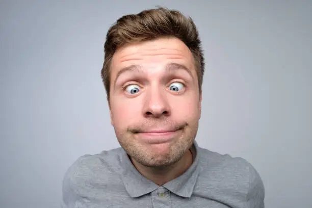 Photo of Young european man looking on nose. His eyes are squinted look.