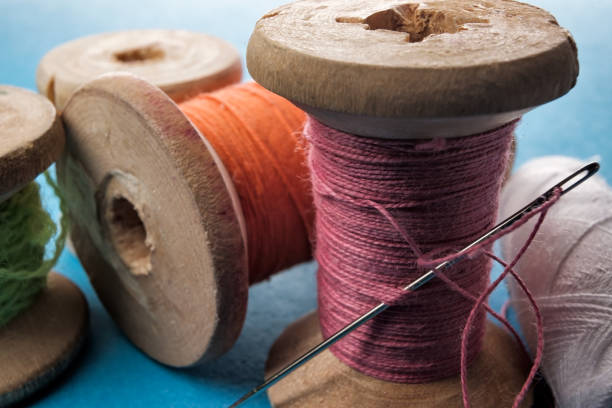 istock Sewing needle and cotton thread on wooden spool macro view. 1147541789