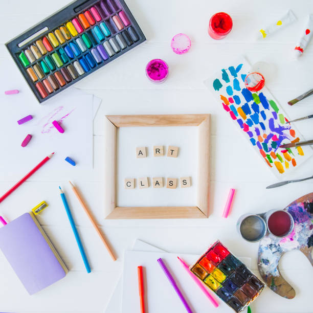 istock Top view creative art class concept. Canvas in frame with lettering inside and many colorful paintiing materials on white wooden background. Drawing lesson for children and adults. Flat lay. Square 1147542647