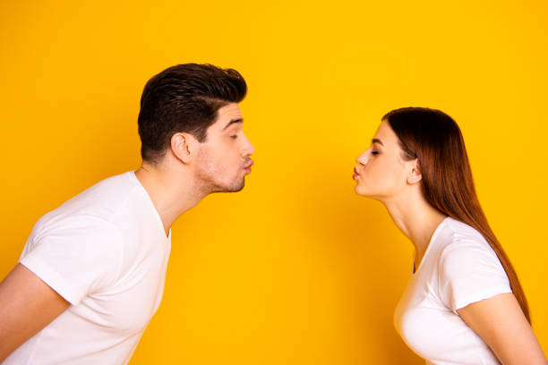 Close up side profile photo amazing beautiful she her he him his guy lady bonding ahead each other need kisses tenderness spread lips wear casual white t-shirts outfit isolated yellow background Close up side profile photo amazing beautiful she her he him his guy lady bonding ahead each other need kisses tenderness spread lips wear casual white t-shirts outfit isolated yellow background. mouths kissing stock pictures, royalty-free photos & images