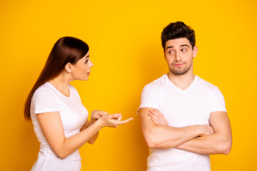 Close up side profile photo two beautiful people she her he him his blame aggression hands arms crossed folded not listen care lecture scolding wear casual white t-shirts isolated yellow background.