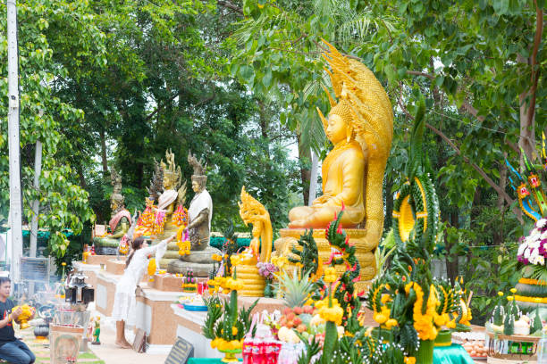 Scene at temple Kamchanod in Udon Thani province: thai people are praying and placing flowers and candles to buddha and nakhon statues. Kamchanod in Ban Dung is popular place for Naga mythology in woods.