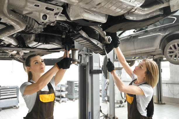 istock Two girls fixing lifted auto undercarriage, using wrenches. 1147546777