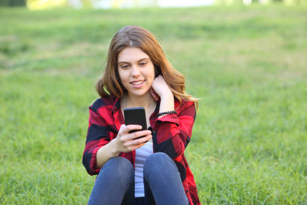 istock Happy teen using smart phone on the grass 1147546967