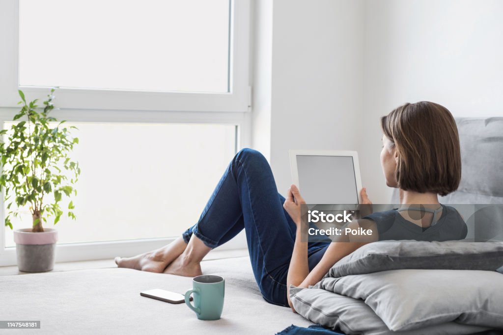 Young woman using digital tablet at home Beautiful student girl using tablet computer in her room. Home work or study, freelance concept Digital Tablet Stock Photo