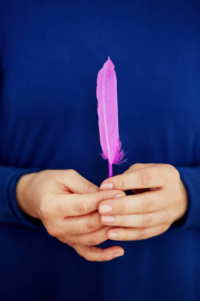 istock Feather of a bird in female hands 1147550574
