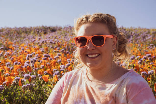Woman with blond braided hair and sunglasses poses in a poppy field during a super bloom. Concept for spring allergies Woman with blond braided hair and sunglasses poses in a poppy field during a super bloom. Concept for spring allergies antelope valley poppy reserve stock pictures, royalty-free photos & images