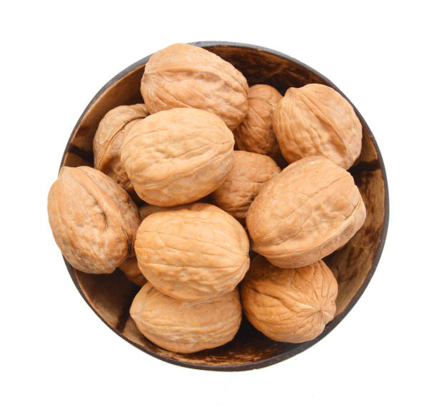 istock walnuts in wooden bowl on white background 1147555237