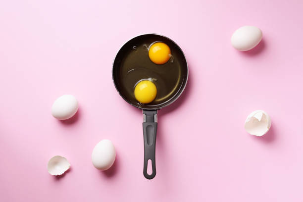 istock Food concept with two eggs, shells, pan on pink background. Top view. Creative pattern in minimal style. Flat lay. 1147558700