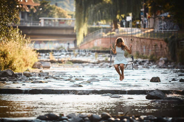 Young woman swings over stream