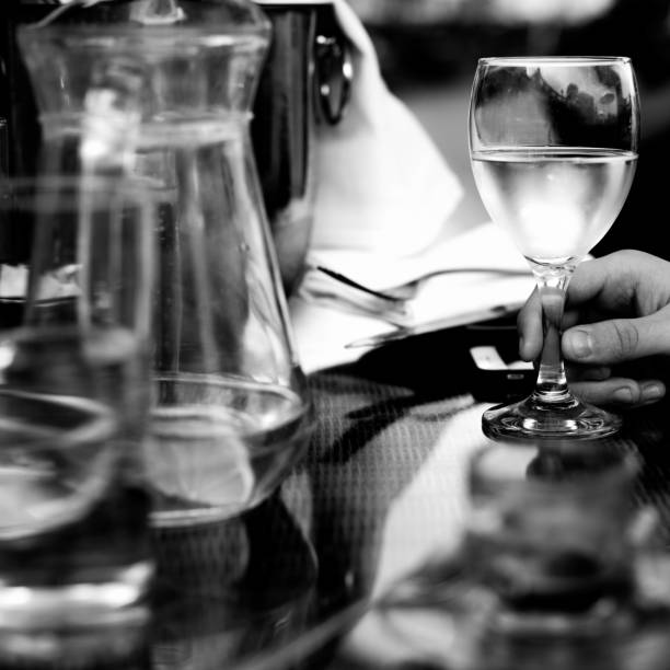 Hand Holding A Glass Of White Wine in a Table setting