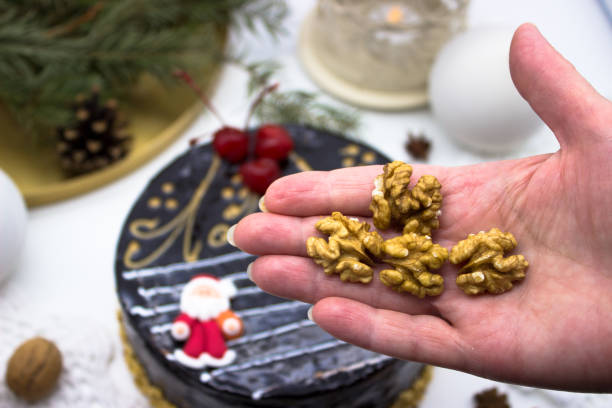istock A hand that holds walnuts. In the background, a delicious chocolate cake decorated with cherries and Christmas decorations. 1147568591