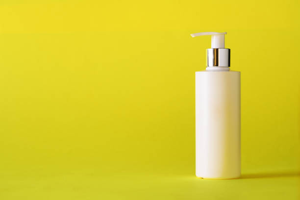 istock White bottle of moisturizing lotion on yellow background with copy space. Minimalism style. Skin care, body treatment, beauty concept 1147568899