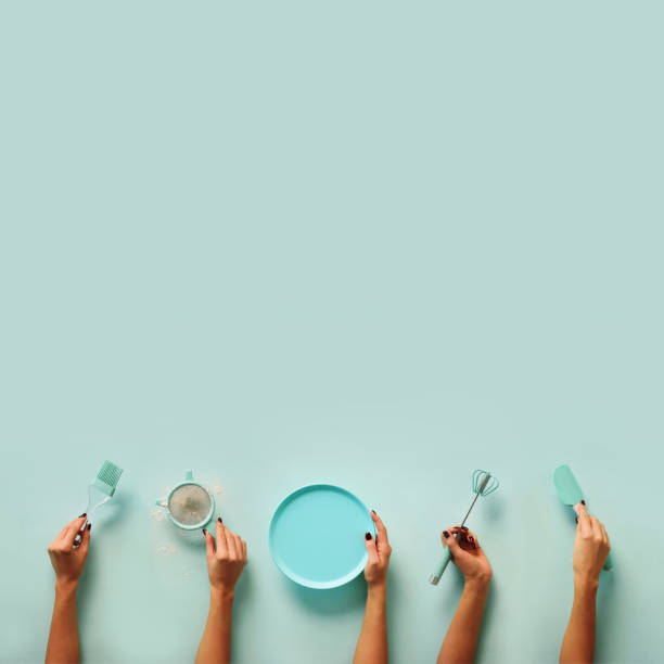 istock Female hands holding kitchen tools, sieve, rolling pin, plate, sieve, brush, whisk, spatula for baking and cooking over pastel blue background. Food frame, bake concept with copy space. 1147568959